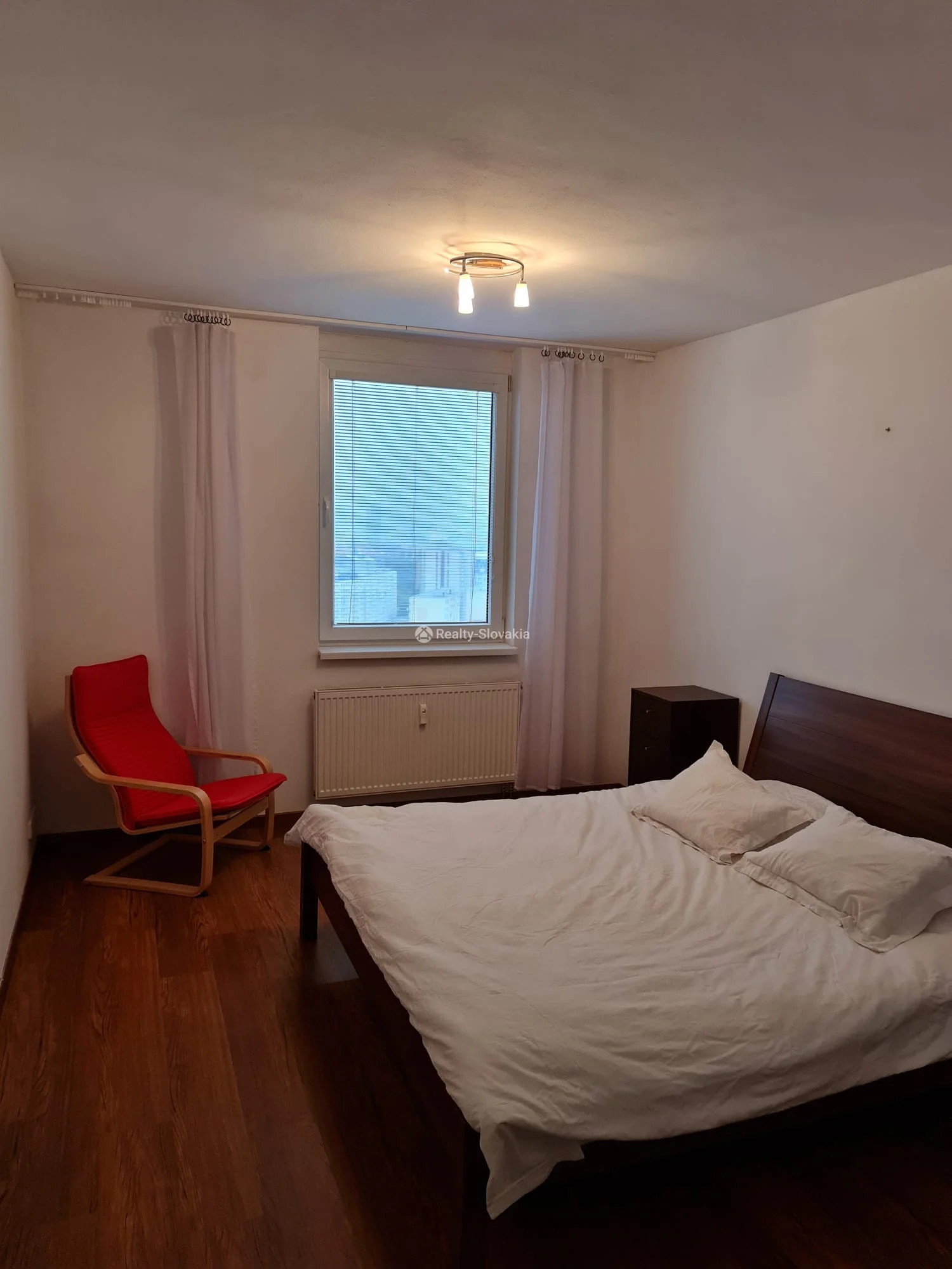 Спальня с кроватью и красным креслом — 2-к квартира, аренда, Братислава
