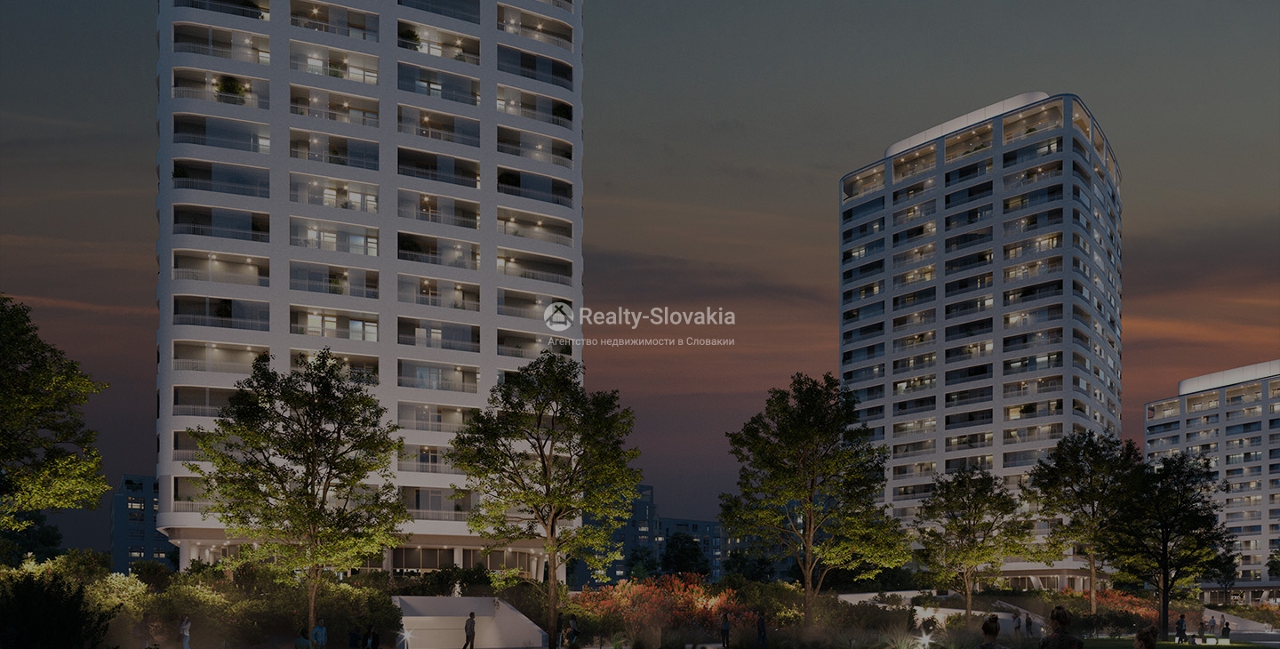 Проект Slnečnice Nad Mestom: Две светлые башни с подсвеченными окнами в сумерках